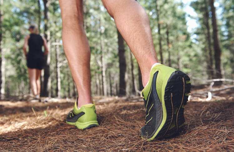 A runner follows an off-road trail through the woods